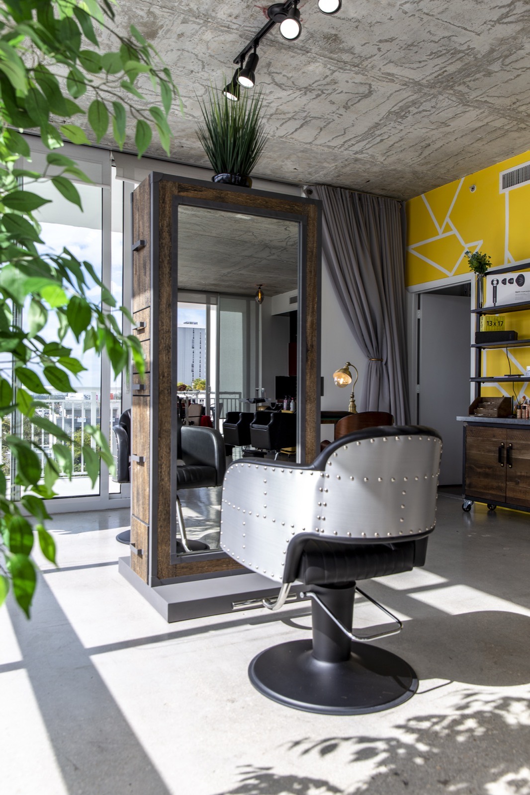 Riveted silver styling chair in front of a reclaimed-wood mirror station